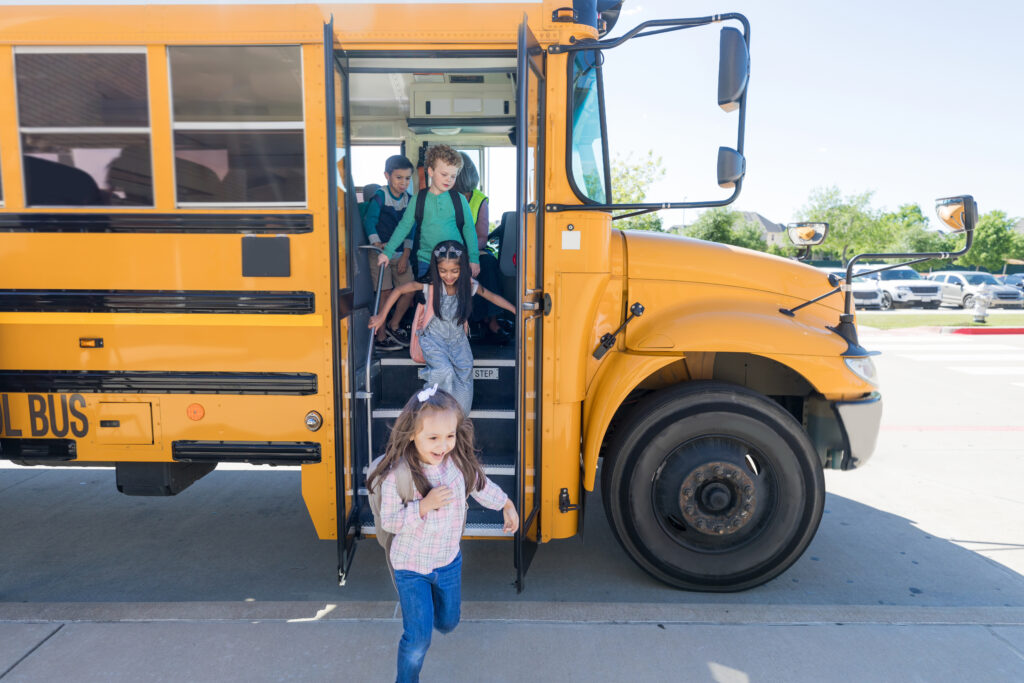 A group of elementary school children exit bus on the first day of school.