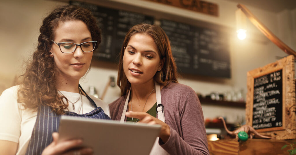 two women at small business with tablet by register