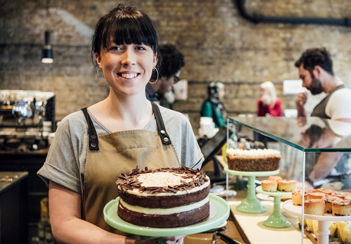 Woman working at a bakery with a cake