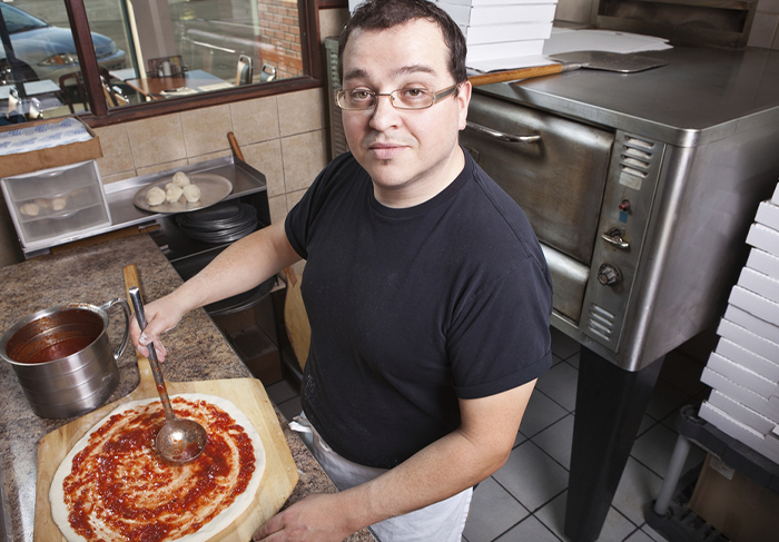 Pizzeria worker making pizza