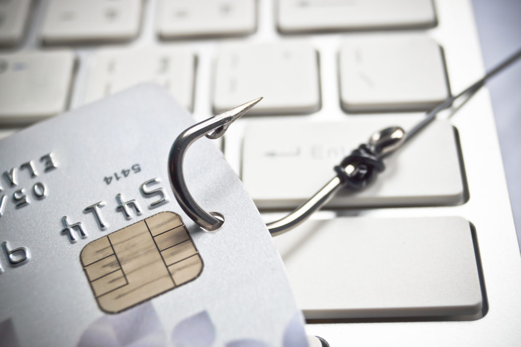 graphic demonstrating phishing internet scams - hook through credit card on keyboard