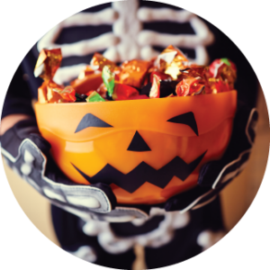 child holding pumpkin bucket full of trick-or-treating candy on halloween