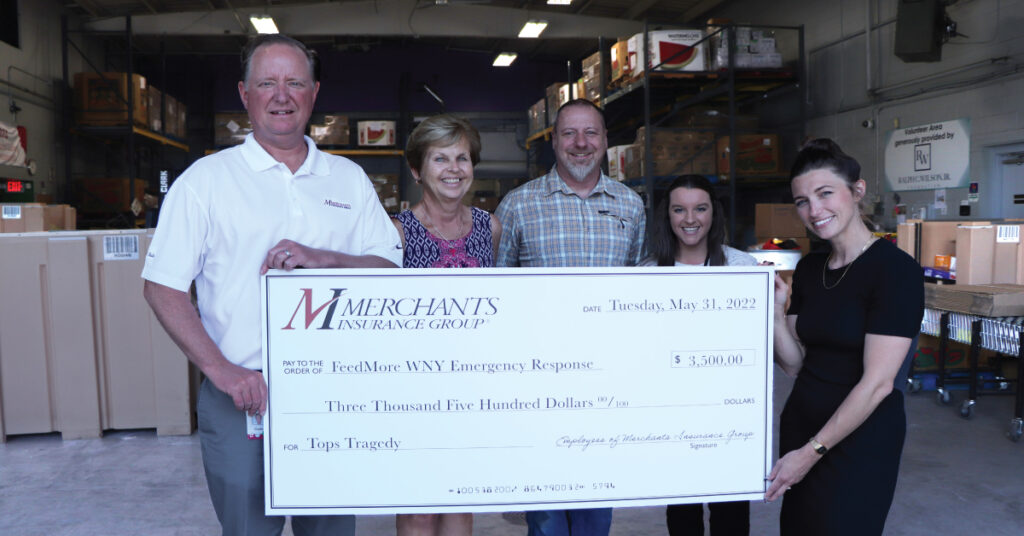 Merchants Insurance Group colleagues giving monetary donation to FeedMore WNY