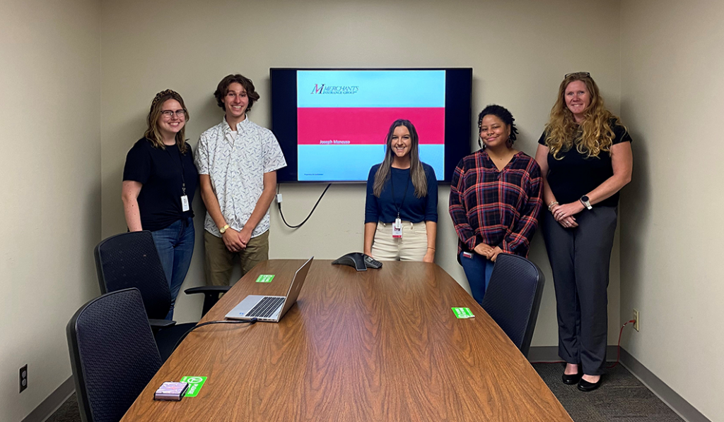 Social Media Intern Joe Mancuso presents his internship project to the corporate marketing department. From left: Katherine Trautwein, Content Marketing Specialist; Joe Mancuso, Social Media Intern; Erica Dalton, Marketing Supervisor; Kyra-Jade Lewis, Associate Video Developer; Wendy Steele, Senior Marketing Design Specialist