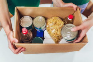 Volunteer with box of food donations, one way to help neighbors in need!