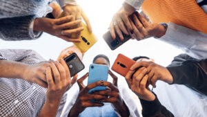 Teens in circle holding smart mobile phones - young people using cellphones outside