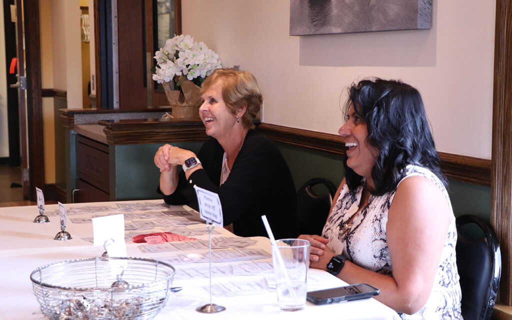 Janice Wojtanik and Lisa Grajeda hand out nametags and drink tickets at the check-in table at the colleague outing