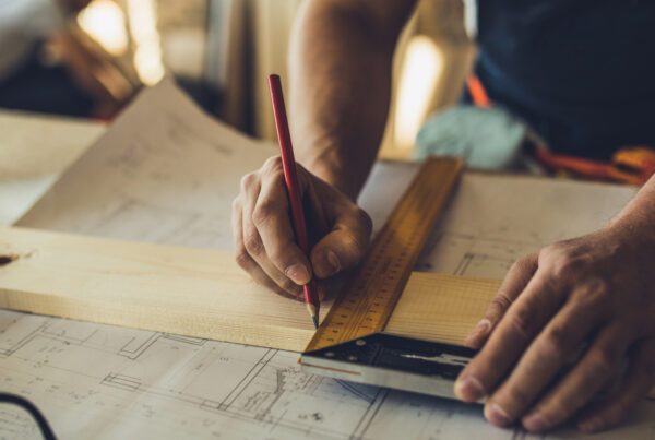 contractor using pencil to mark measurements on wood with ruler