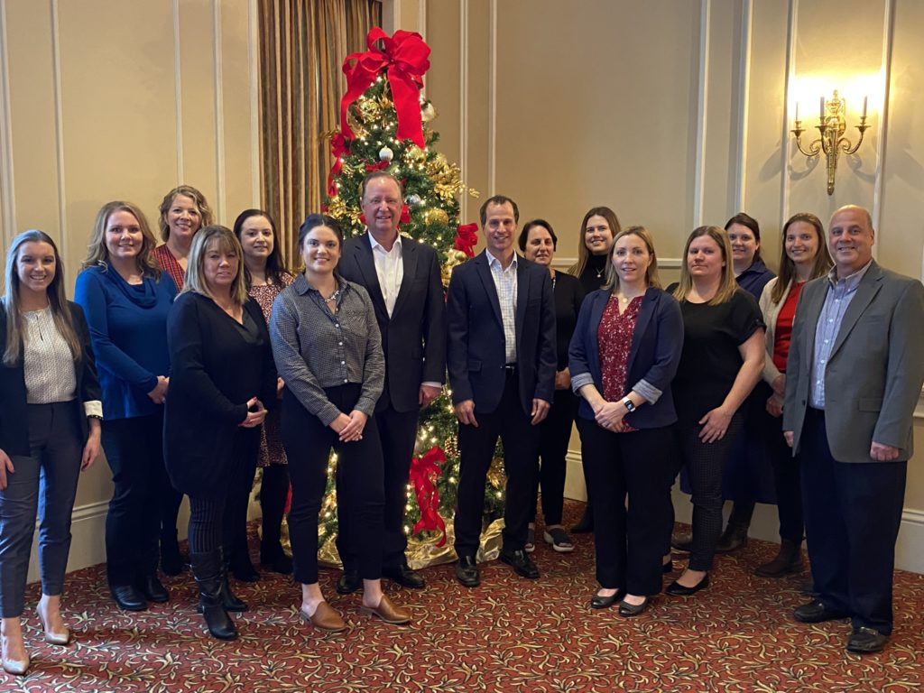 Merchants' United way committee smiles in front of Christmas tree with Charles Makey, President of Merchants Insurance Group