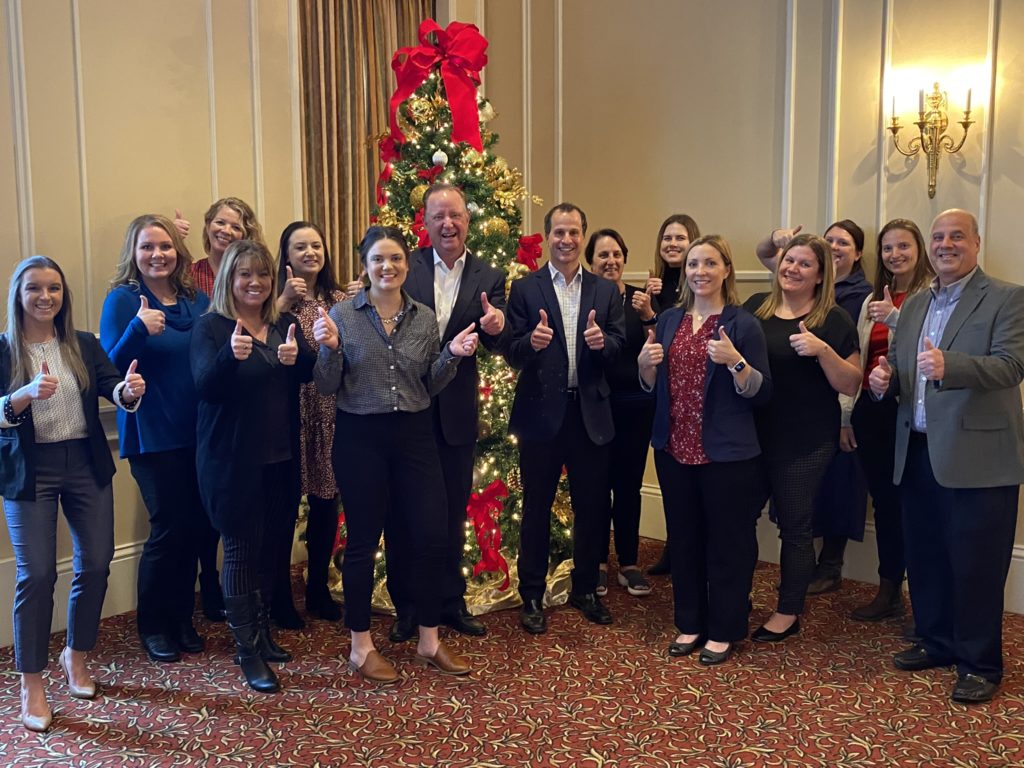 Merchants' Corporate United Way committee gives a thumbs up with company president Charles Makey in front of a Christmas tree at the Buffalo Club!