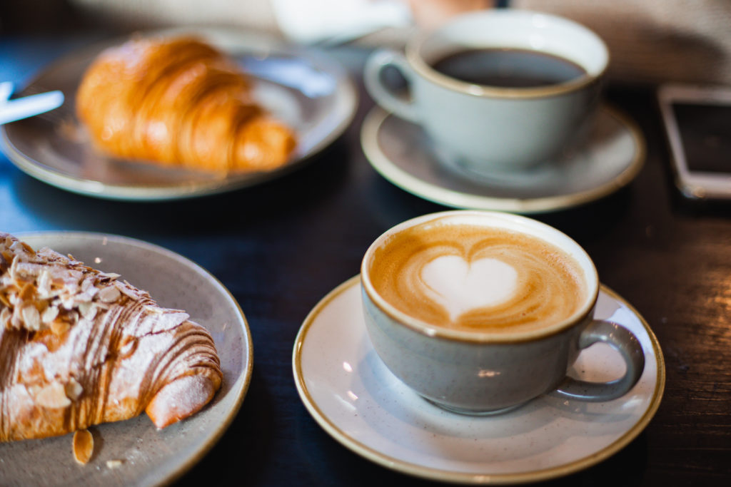 pastries, coffee, and latte with heart design on table at coffee shop on Valentine's Day