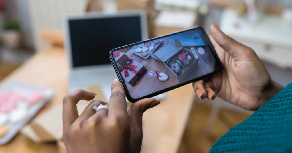 Photo of. person's hand taking a picture of Valentine's Day products, as suggested in Valentine's Day marketing tips