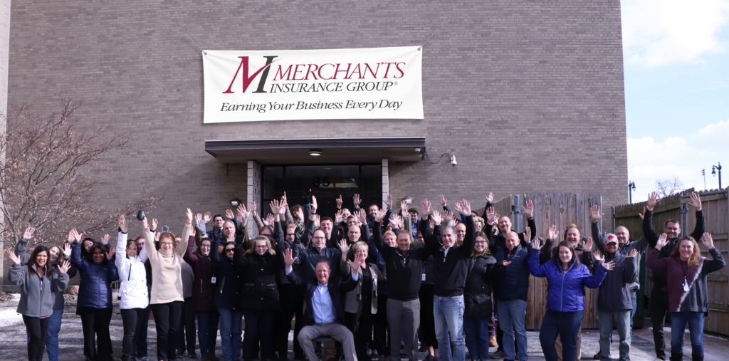 Merchants colleagues raise their hands in the air outside Merchants Insurance Group corporate office in Buffalo, NY, celebrating that we were named among Business First's "Best Places to Work in Western New York"