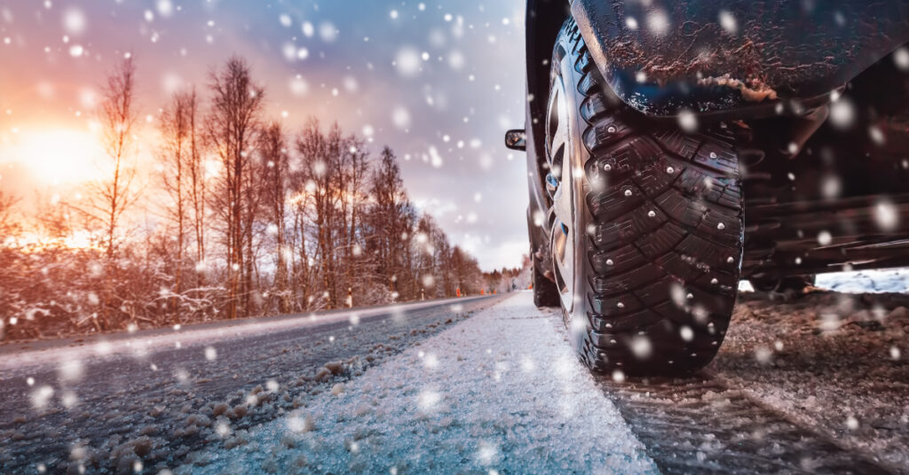 photo of car tire driving on snowy road to indicate driving in unpredictable weather