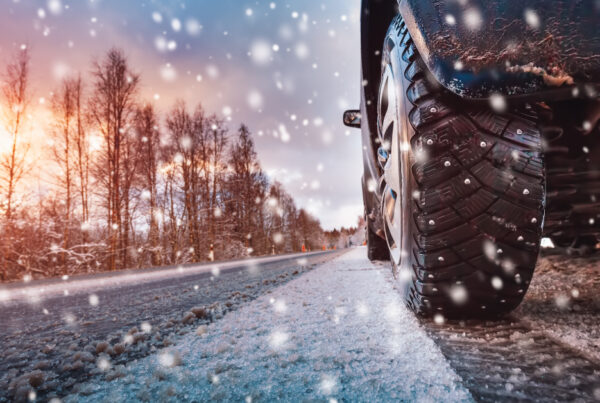 photo of car tire driving on snowy road to indicate driving in unpredictable weather