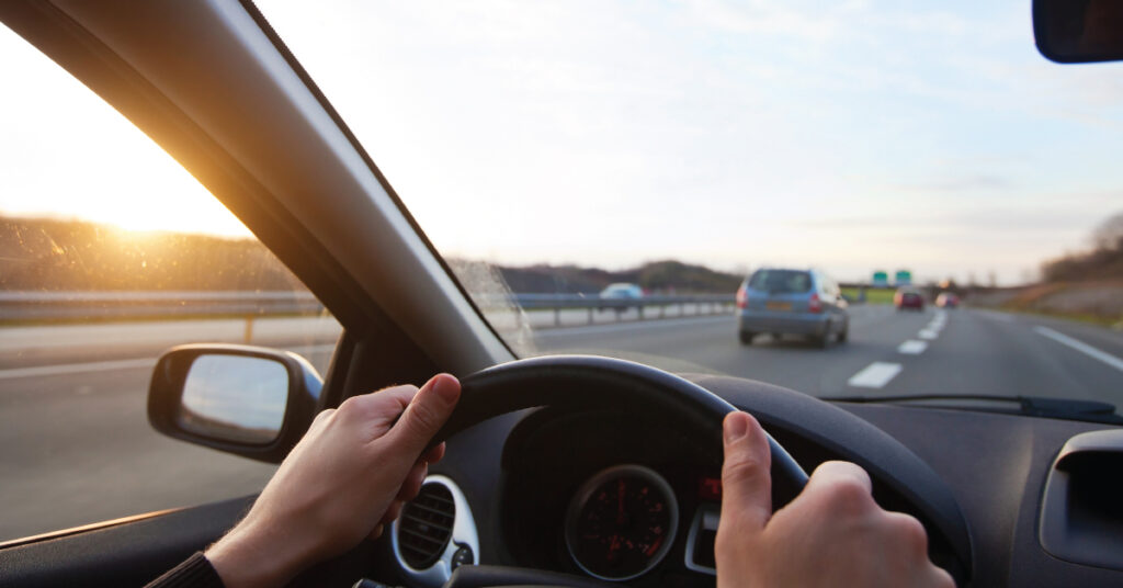 hands on steering wheel, driving on highway, person is prepared for road trip emergency