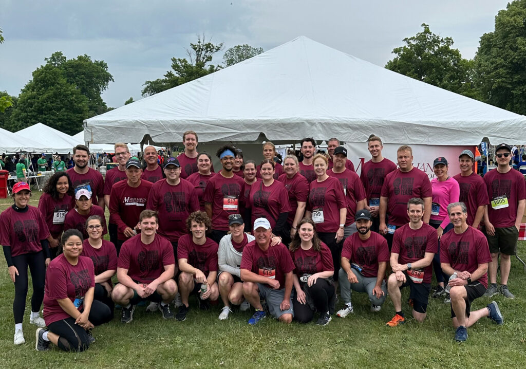 Group photo of Merchants Insurance Group's Corporate Challenge team in front of company tent, 2023