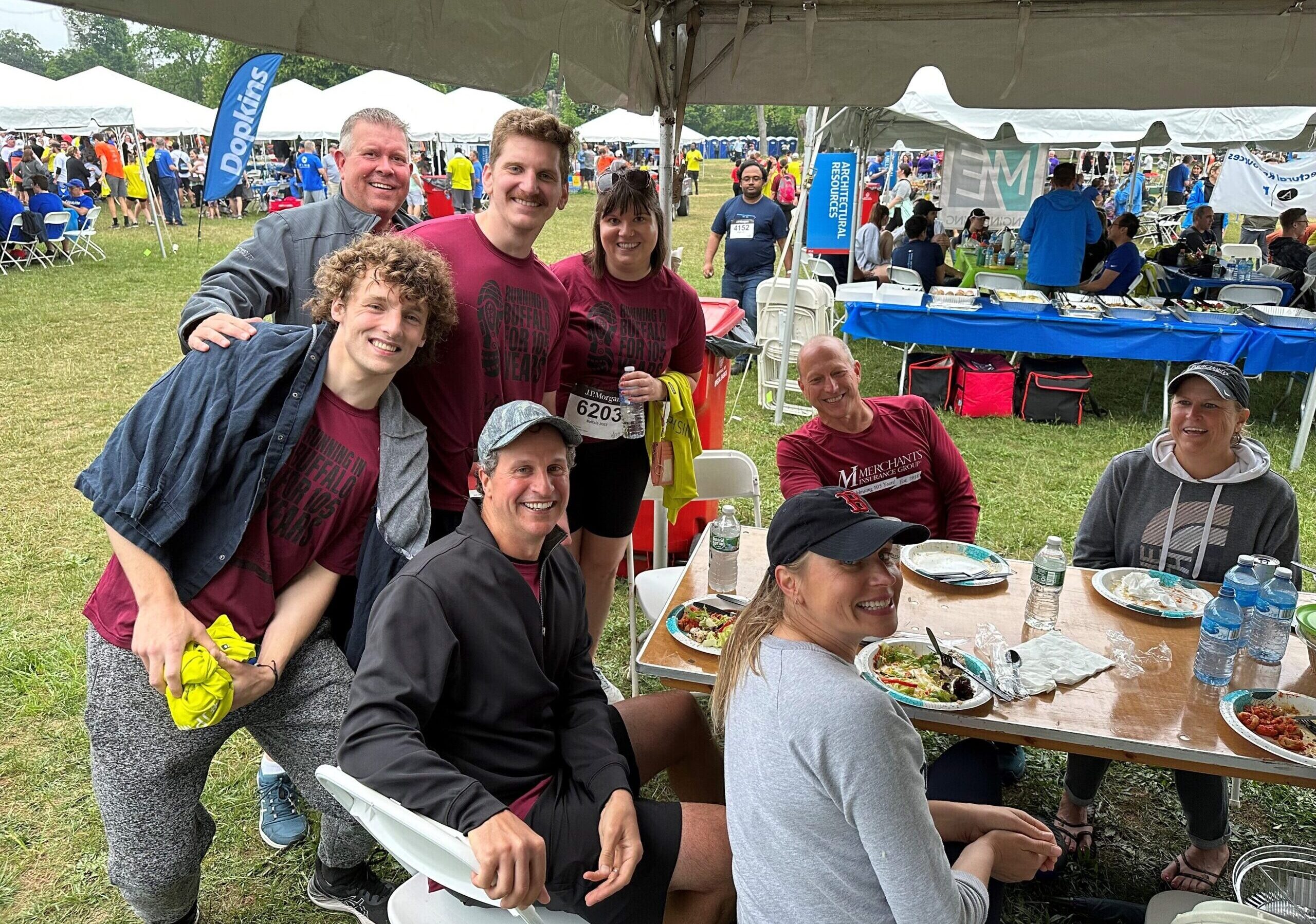 Merchants colleagues smile at the company tent, eating dinner after the Corporate Challenge