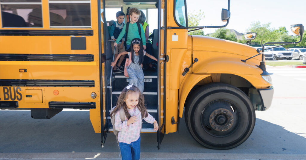 Children getting off bus on first day of school after arriving at school safely