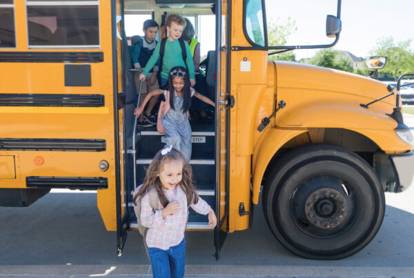Children getting off bus on first day of school after arriving at school safely