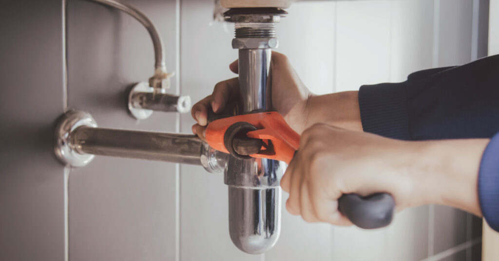 plumber working on pipes under the sink