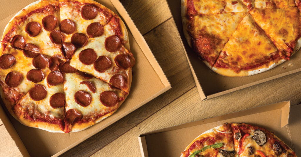 three pizzas on a table at a pizzeria