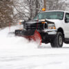 White truck snow plow driving on snowy road, snow plow business at work during winter