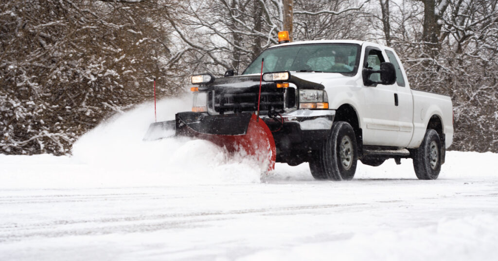 White truck snow plow driving on snowy road, snow plow business at work during winter