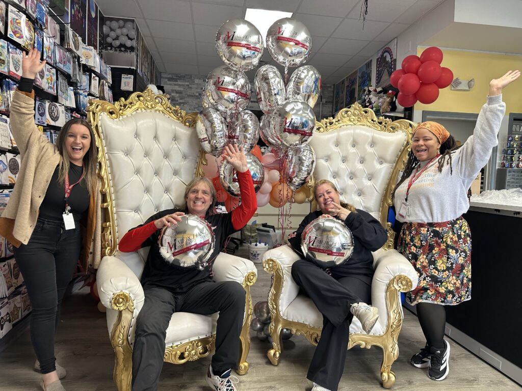 Merchants Insurance Group colleagues visit Balloon Masters, pose for photo with large chairs and Merchants Insurance Group balloons